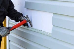 As part of an exterior house renovation, damaged plastic siding is being replaced