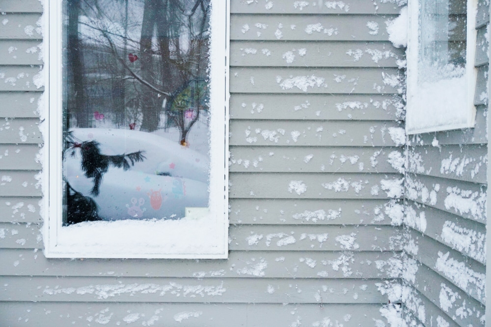 Wooden house covered in snow after a blizzard